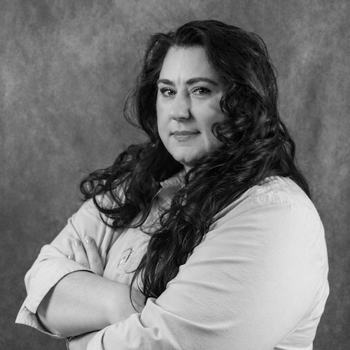 Margaret Farrand, Director of Sales and Marketing, with long dark hair with purple highlights, smiles.