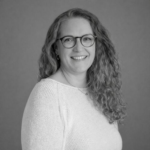 Black and white pic of smiling woman in glasses with long hair. Rachael Vierschilling at Harmony Design Group.